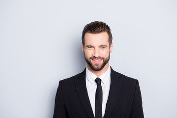 Portrait of positive joyful business person with modern hairstyle and elegant outfit, wearing black suit with tie looking at camera, isolated on grey background