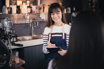 Asian women are getting orders from customers at coffee shop counter