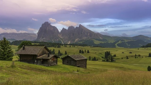 Timelapse video of the Sassolungo mountains on the Italian Alps Dolomites with wood houses on the foreground