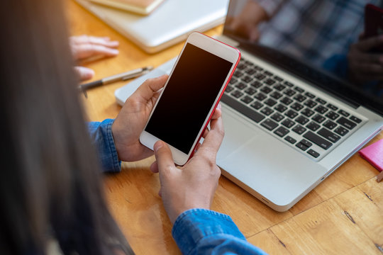 Businesswoman hands holding and using mobile smartphone in office.  and computer screen.Close up