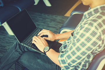 young man using laptop and business chart while while waiting for her flight at airport terminal ;business travellers waiting for their flight at airport