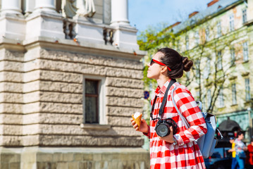 Fototapeta na wymiar woman walking by city with camera and ice cream. copy space