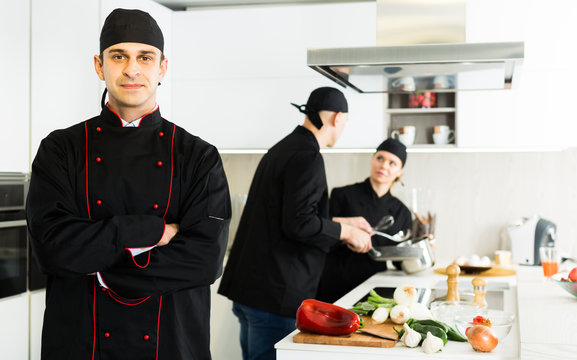 Professional chef  in black uniform standing  near workplace