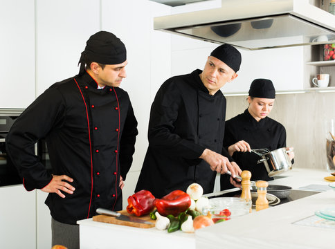Professional chefs  in black uniform  working with vegetables
