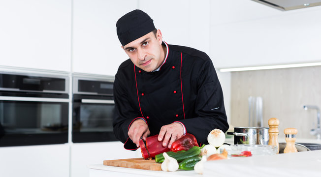 Professional chef  in black uniform preparing vegetables on kitchen