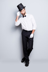 Full size fullbody portrait of stylish attractive magician in tophat, formal wear,  looking at...
