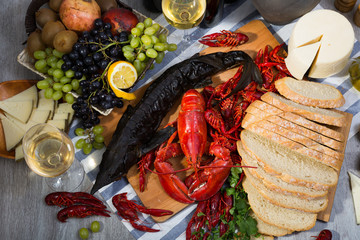 Top view of smoked sturgeon, lobster, crayfishes, bread, cheese, fruits and wine