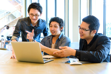 Group of Asian Business man or student in casual suit meeting and looking presentation project on thier laptop in the modern office or coffee shop, Project and Business concept