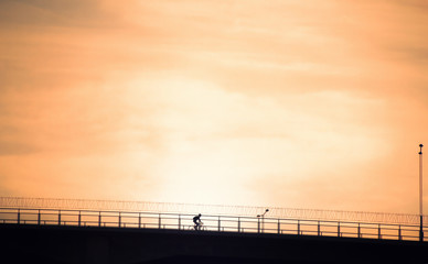 A man who is riding bike to sunset.