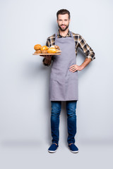 Full size body portrait of positive attractive baker in jeans, shoes, shirt, apron with stubble...