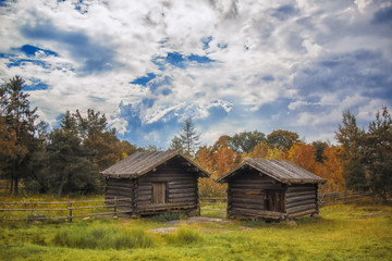 Traditional wooden hut or cottage in grass with clouds.