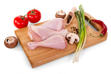 Poultry meat - chicken legs and vegetables on cutting Board isolated on white