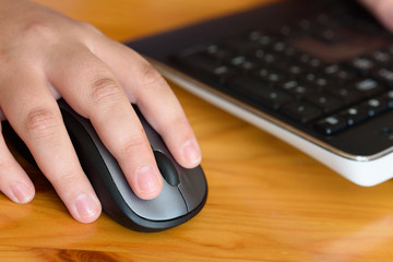 Persons hand using a computer mouse on a wooden desk