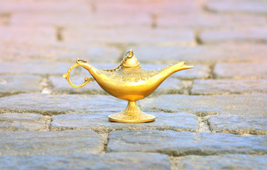 Beautiful Aladdin lamp on stones. Oriental fairy tale concept of fulfillment of desires with the help of a miracle.