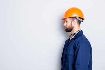 Profile side view portrait with copy space, empty place for advertisement product of virile harsh repairer in blue uniform, standing over grey background