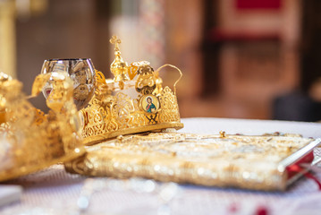 Crowns for a orthodox wedding ceremony, a glass of wine and religious book.