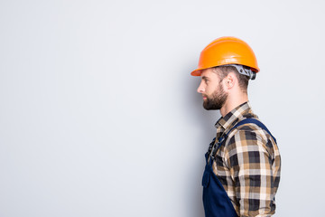 Profile portrait with copy space, empty place for advertisement, product of virile harsh repairer in shirt and overall isolated on grey background