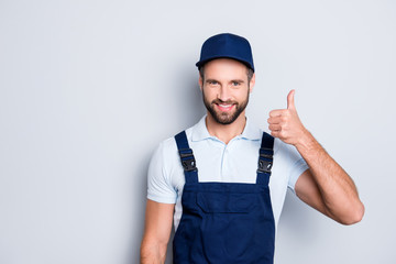 Portrait of cheerful positive deliver in blue uniform with stubble showing thumb up with finger...