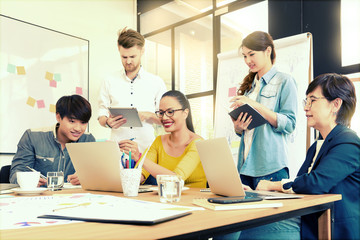 Asian young man business officer explaining internal meeting to his project team in modern office. They are the multi ethnic business person group in casual suit. Project and Business concept.