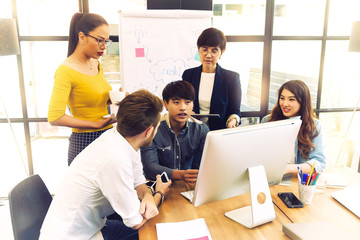 Asian young man business officer explaining internal meeting to his project team in modern office. They are the multi ethnic business person group in casual suit. Project and Business concept.