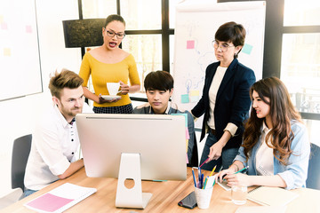 Asian young man business officer explaining internal meeting to his project team in modern office. They are the multi ethnic business person group in casual suit. Project and Business concept.