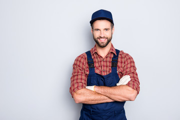 Portrait of handsome mechanic with stubble in blue overall, shirt having his arms crossed, looking at camera, isolated on grey background - obrazy, fototapety, plakaty