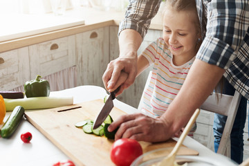 Little girl and dad having fun while cooking in kitchen