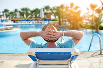Relax in the pool summer. Young and successful man lying on a sun lounger at the hotel on the...