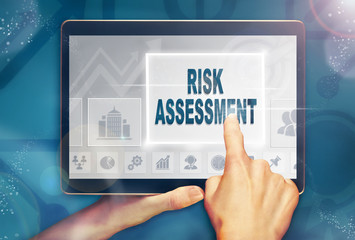 A hand selecting a Risk Assessment business concept on a computer tablet screen with a colorful background.