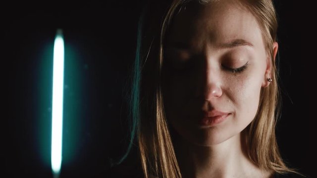 A woman is crying in the dark. She is very sad. Tears flow down her cheeks. 4k