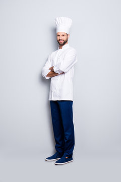 Full size body portrait of joyful positive chef cook with stubble in beret, having his arms crossed, isolated over grey background, looking at camera