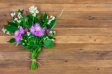 bouquet of flowers of clover, cornflowers and Jasmine on a wooden retro brown background with copy space