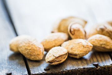 Roasted almonds in shell on the rustic background. Selective focus.