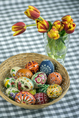 Homemade handmade painted Easter eggs on wicker basket, traditional handcraft eggs