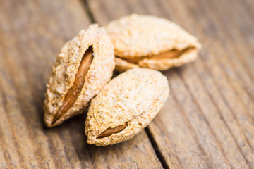 Roasted almonds in shell on the rustic background. Selective focus.