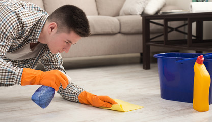 Young man cleaning home with detergents
