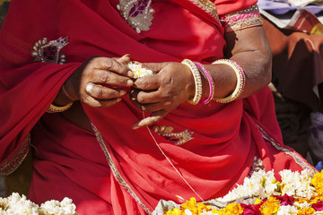 Indian female hands making fresh flower necklace for selling