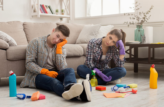 Tired couple with cleaning equipment at home