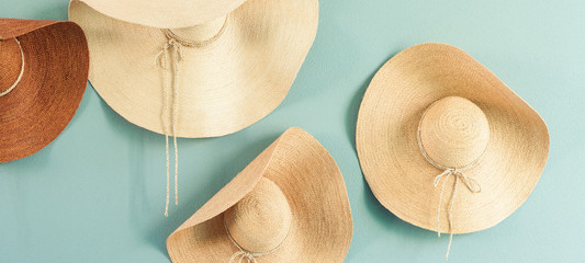 Various summer hats hanging on the pastel color wall, basketwork hat for decoration in house.