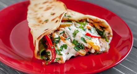 Shaarma with meat, onions, tomato, lettuce lies in a plate on a dark old wooden table.Greek food