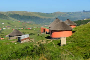 Fotobehang Afrika Rondawels, traditionele hutten met rieten daken verspreid door de met gras begroeide heuvels in een dorp in de buurt van Coffee Bay aan de Wild Coast in Oost-Kaap, Zuid-Afrika  © Alexandre ROSA