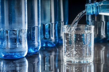 Mineralwasser in ein Glas eingeschenkt auf spiegelndem Tisch, Hintergrund