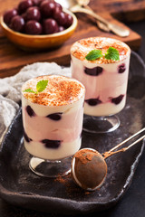 Dessert in glasses. Layered dessert made from cream with canned cherries. Country style.