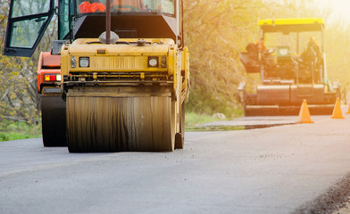 Heavy vibration rollers and different machines working at paving new road in the sunset