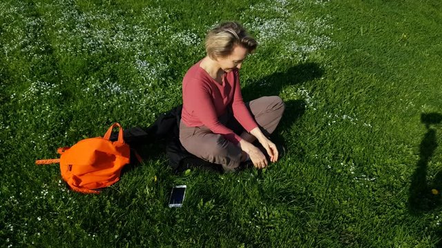 Adult Woman sitting on green grass with mobile phone