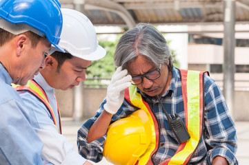 Asian civil engineer team wearing safety helmet and uniform using blueprint to meeting, discussing brain storm for solving their problem situation in middle of city town