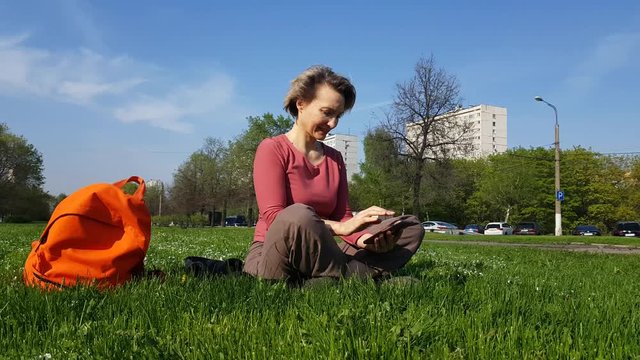 Adult Woman sitting on green grass with mobile phone