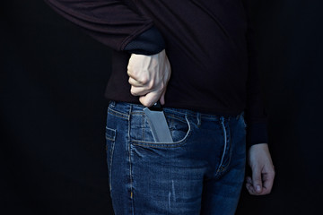 A man takes out a knife from his pants, a black background