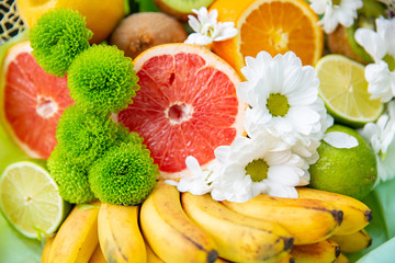 Obraz na płótnie Canvas Tropical Exotic fruits. grapefruit, Banana, lime kiwi orange with flowers