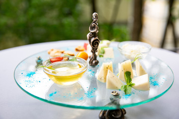 Assortment of cheese. Composition of different varieties of cheese with honey, nuts on glass table.